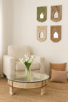 Lifestyle imagination of a round reclaimed wood coffee table with glass top and hand-carved Indian design; hollow interior, 70 cm diameter, 30 cm height.