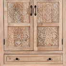 Close up picture of a hand carved mango wood cabinet with floral design, 2 doors and 2 drawers, in a living room scene.