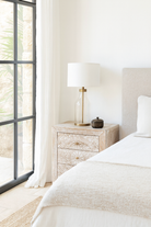 Lifestyle scene with a set of two hand carved night stands in solid mango wood with mandala motifs; white washed furniture, 50 × 40 × 60 cm.