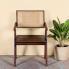 Acacia wood chair Kalyani with rattan backrest and armrests; elegant wooden armchair for dining or living rooms, 55 × 55 × 85 cm.
