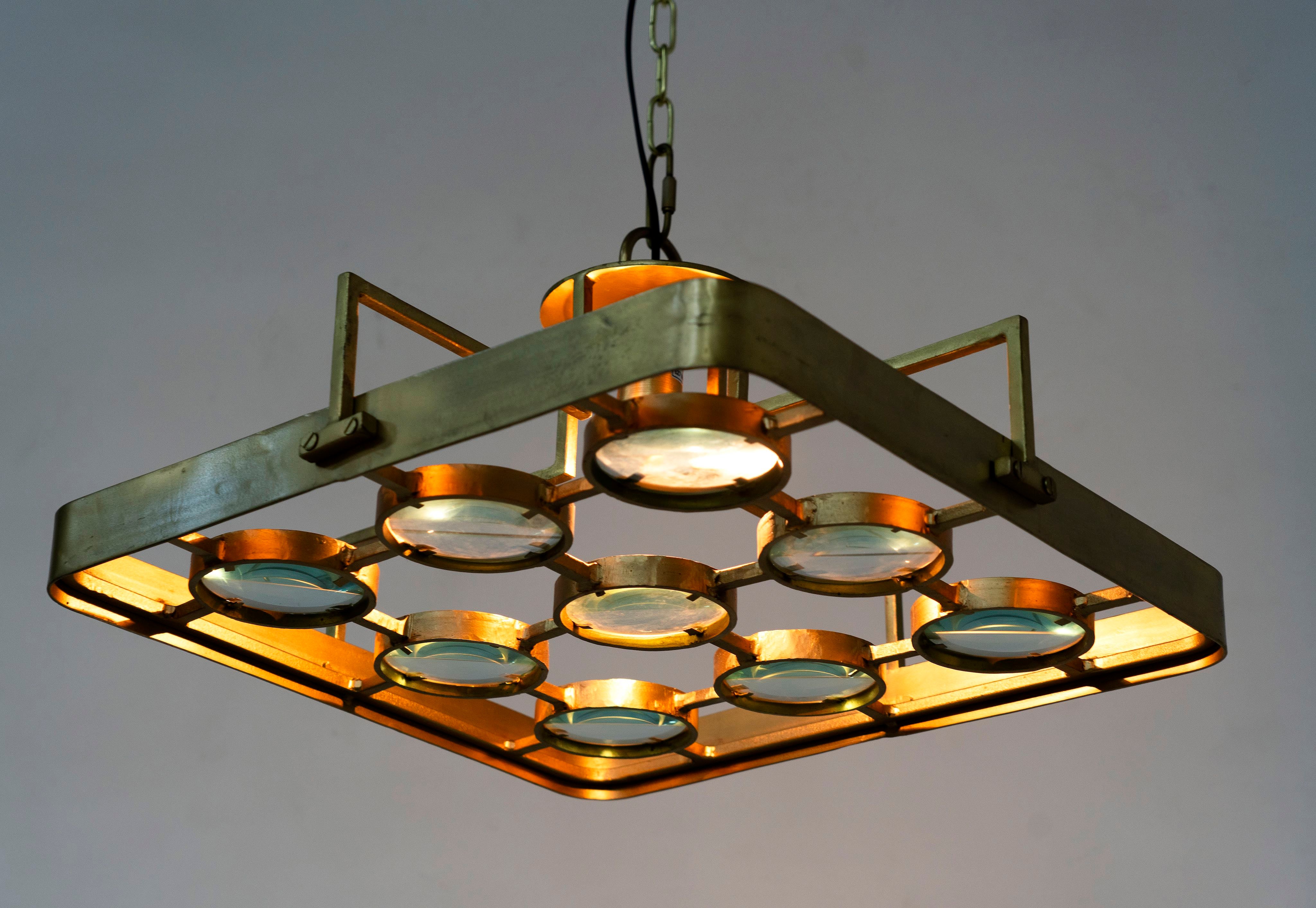 Image with a lighted unique pendant light with square brass-plated iron frame and magnifying blue and white glass inserts – a vintage lighting piece for kitchens, dining rooms, or living areas.