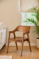 Lifestyle imagination for a wooden armchair made of solid acacia wood with curved backrest and armrests; acacia wood chair, 60 × 50 × 90 cm.