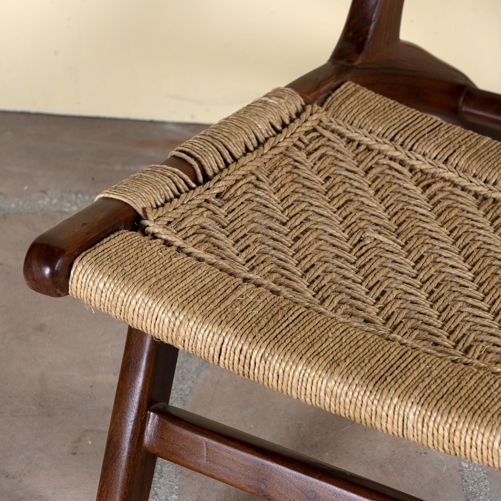 Close up image of an acacia wood chair with handwoven cotton rope seat and backrest; rustic wooden armchair for living rooms or lounges, 60 × 80 × 95 cm.