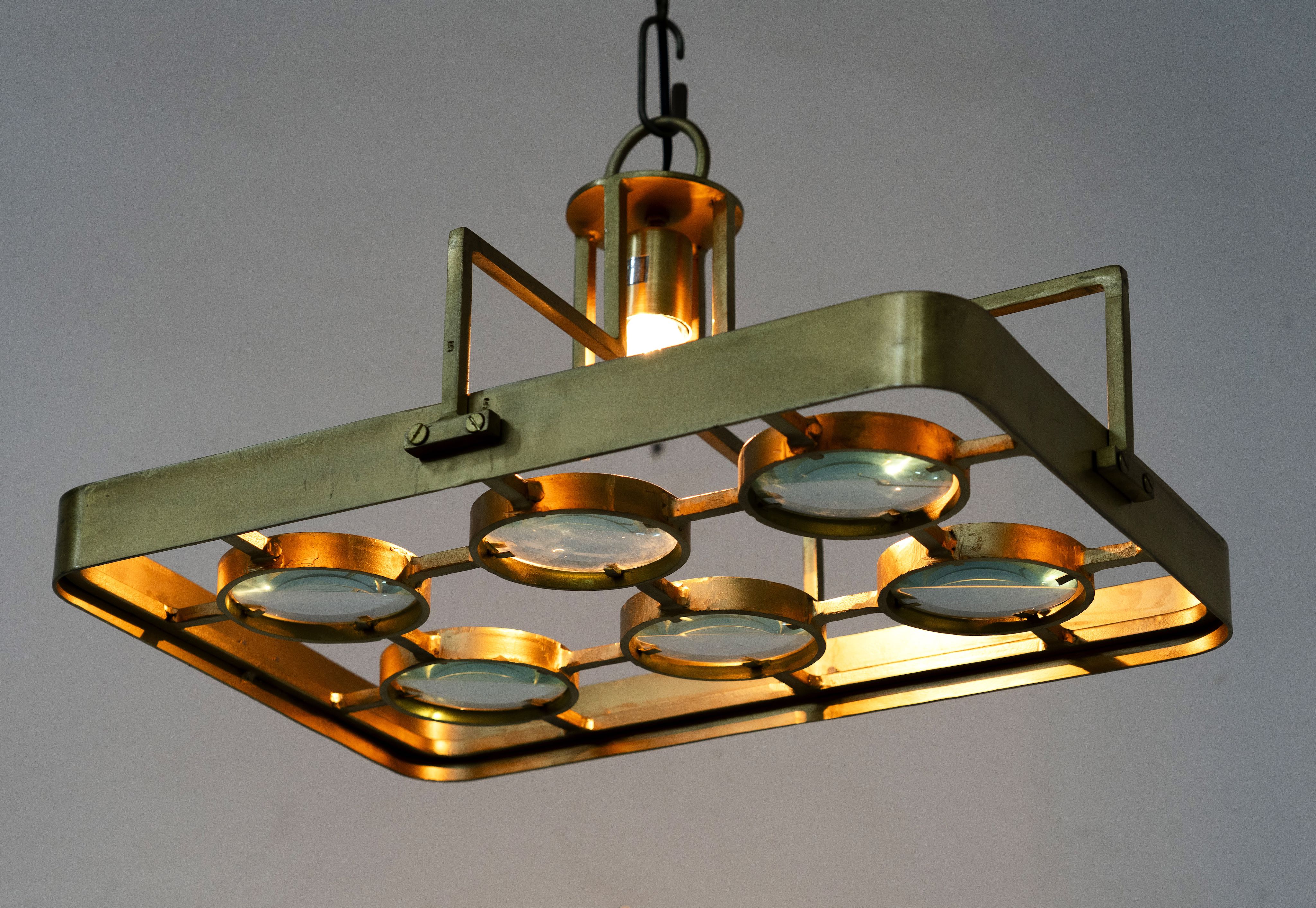 Image showing a lighted unique pendant light with brass-plated iron square frame and magnifying blue and white glass inserts – vintage lighting piece ideal for kitchens, living rooms, or entryways.