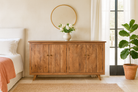 Lifestyle imagination of a sideboard with modern appeal made of acacia wood with brass fitted doorknobs and 4 doors.