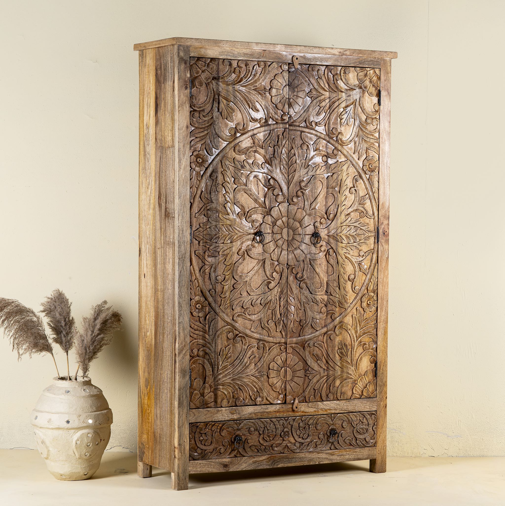 Side view of a hand carved mango wood cabinet with floral design, 2 doors and one drawer in vintage design.