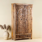 Side angle image of a Mango wood wardrobe with hand-carved floral detailing, Indian carved wooden furniture with bottom drawer, 105 × 40 × 180 cm.