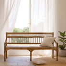 Lifestyle imagination of a hand carved mango wood bench with floral backrest and spindle accents; rustic mango wood seating, 176 × 56 × 95 cm.