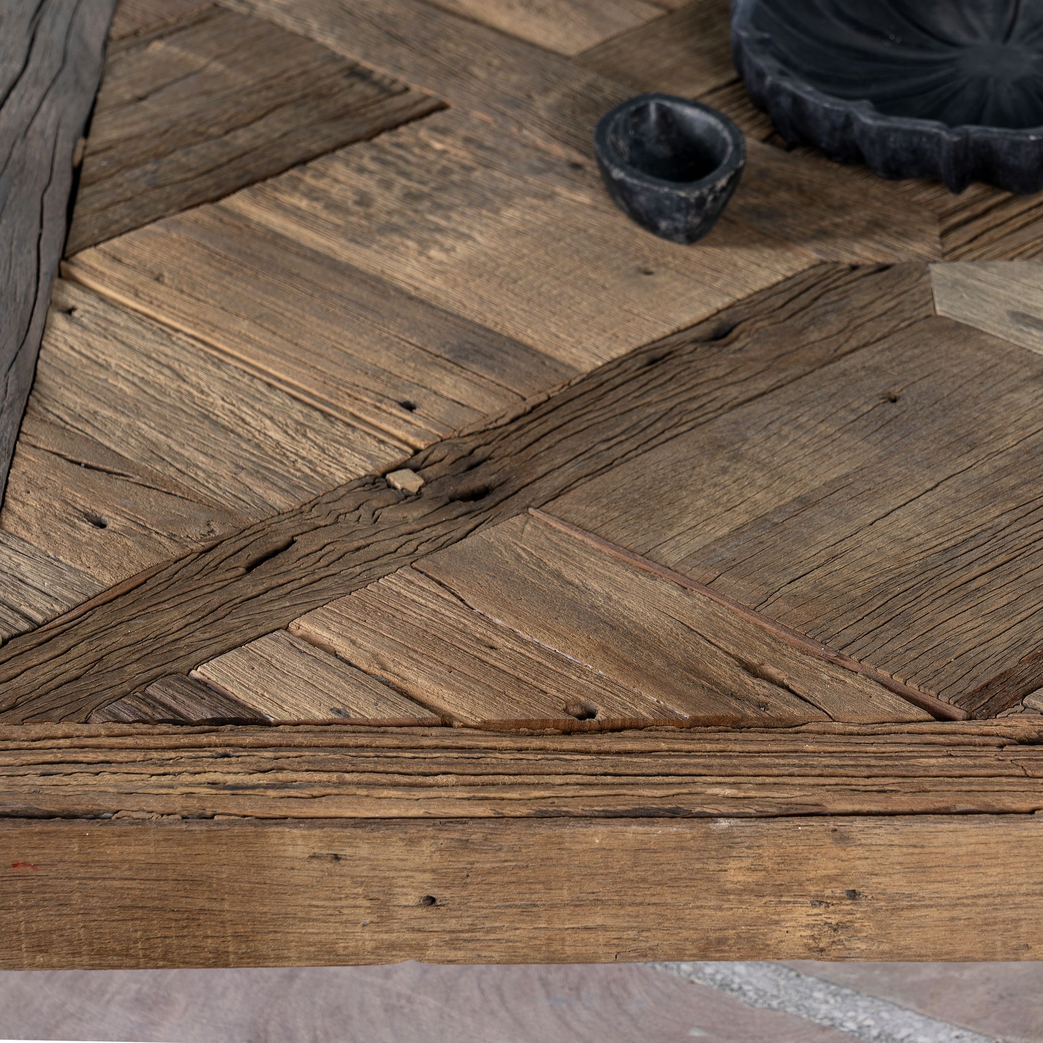 Close up image of a square rustic coffee table made from reclaimed wood, featuring a patterned plank tabletop with a natural distressed finish and sturdy block legs for a solid, handcrafted look.
