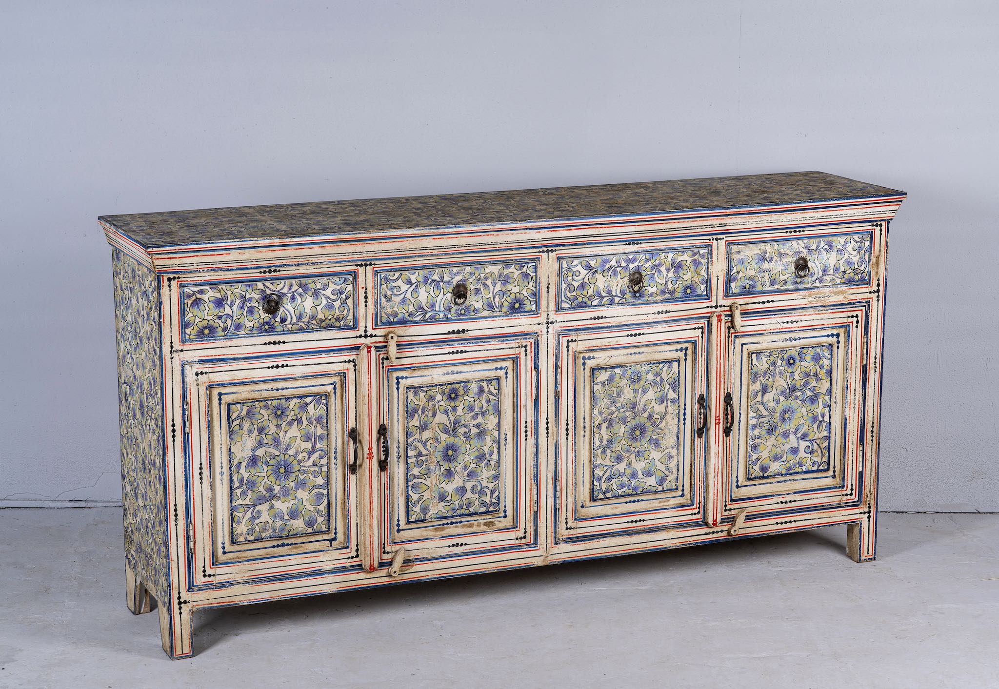 Side angle image of a vintage hand-painted floral sideboard with reclaimed wood frame, blue and yellow floral designs, and distressed multicolour detailing.
