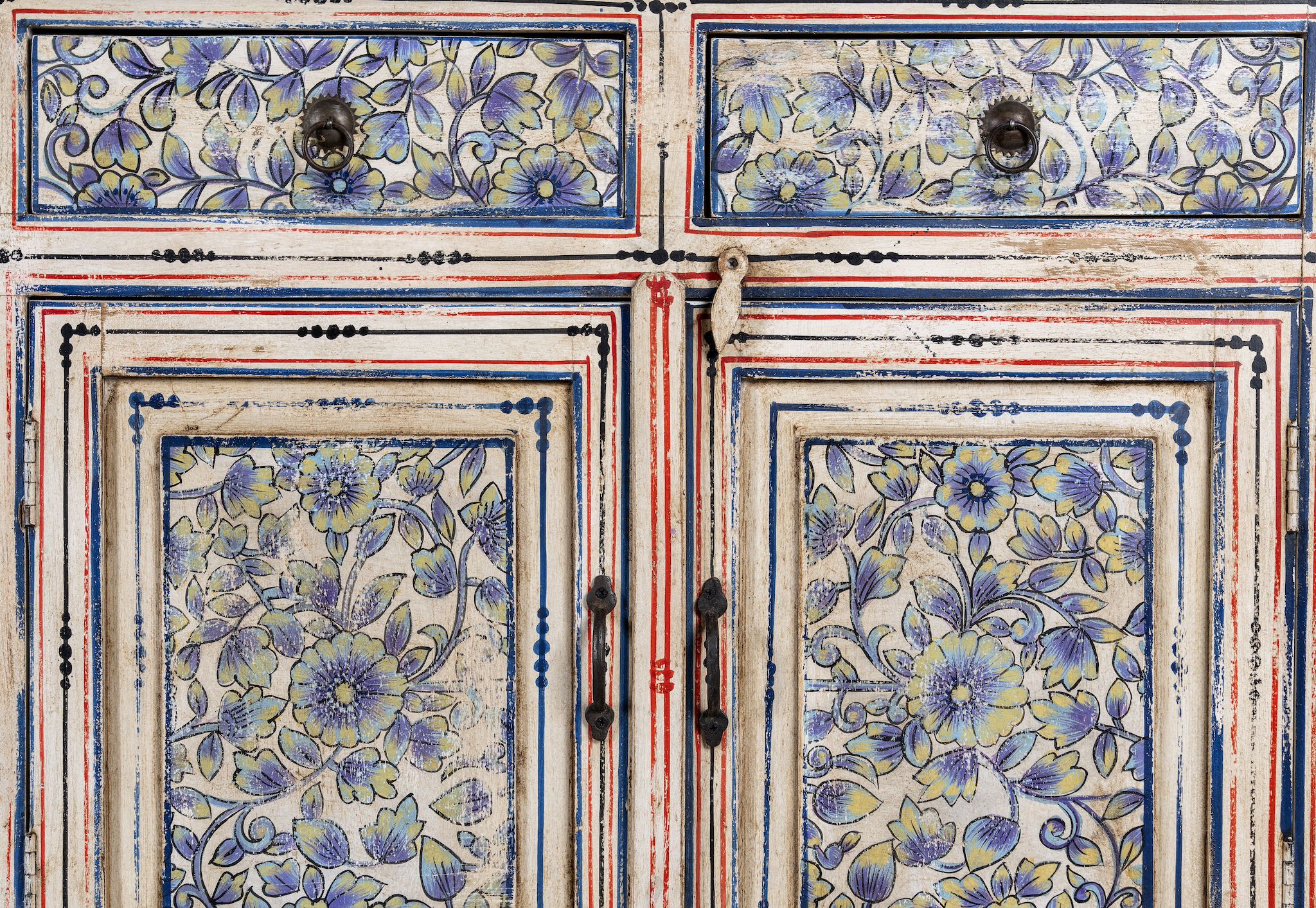 Close up image of a vintage hand-painted floral sideboard with reclaimed wood frame, blue and yellow floral designs, and distressed multicolour detailing.