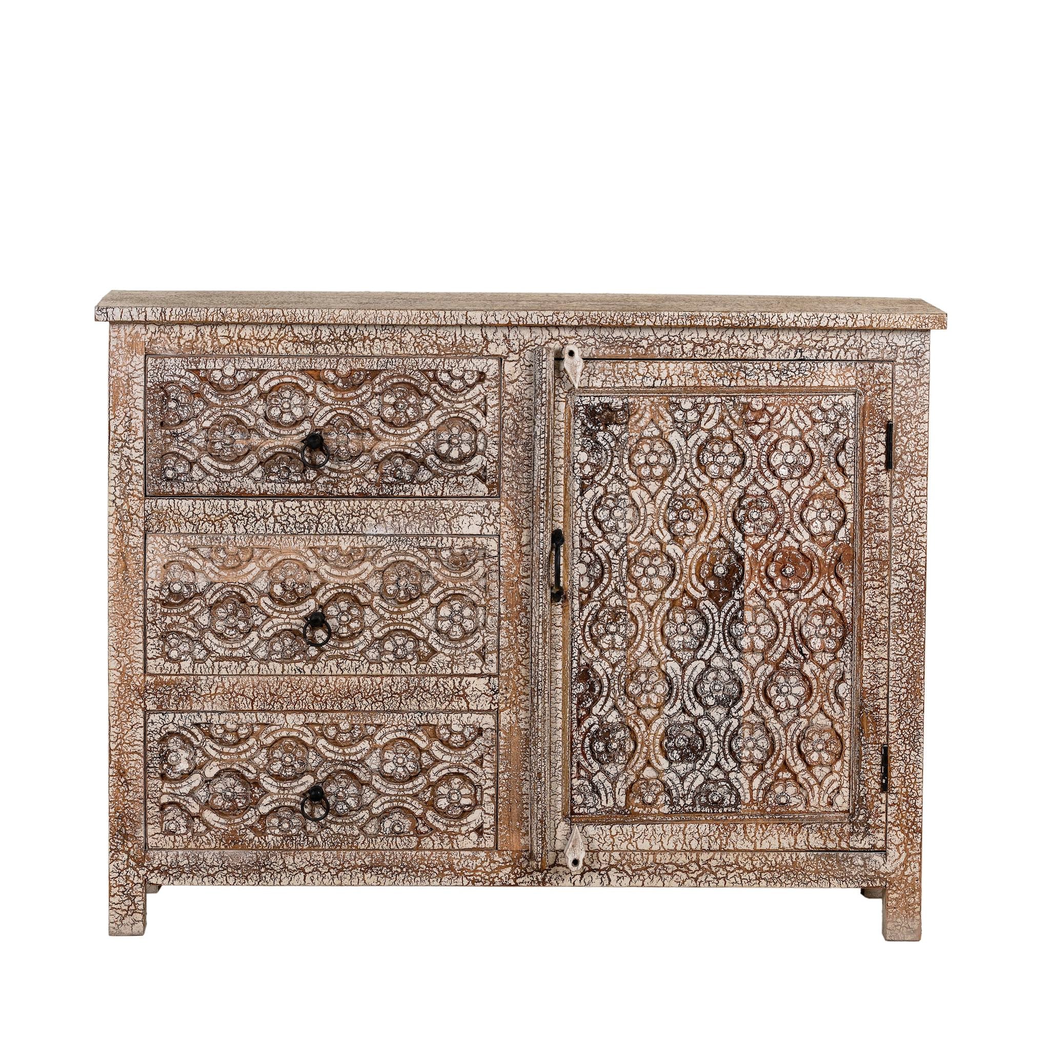 White background image of a hand-carved sideboard made from mango wood, featuring intricate geometric and floral patterns across the drawers and cabinet door, with a distressed whitewashed finish that enhances its vintage artisanal appeal.
