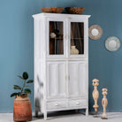 Side angle image of a shabby chic teak wood cabinet with glass doors, drawers, and compartments – sustainable living room furniture crafted from refurbished teak wood with a soft white finish.