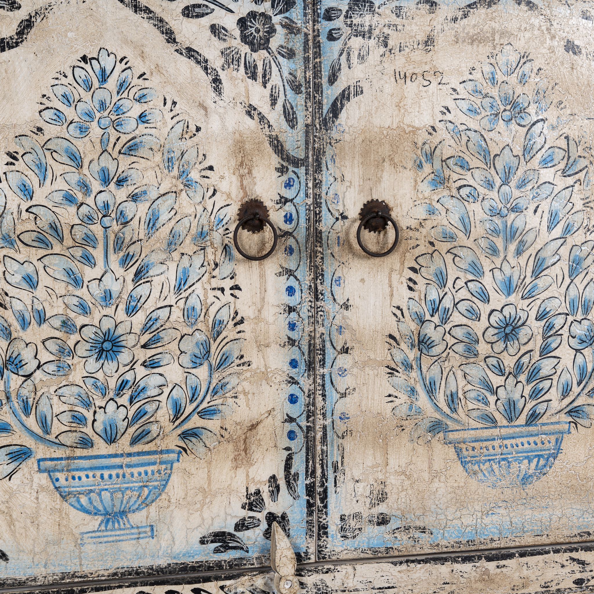 Close up picture of a vintage-style cabinet made from reclaimed wood, featuring intricate hand-painted floral vases in soft blue tones and distressed black detailing for an artisanal heritage look.