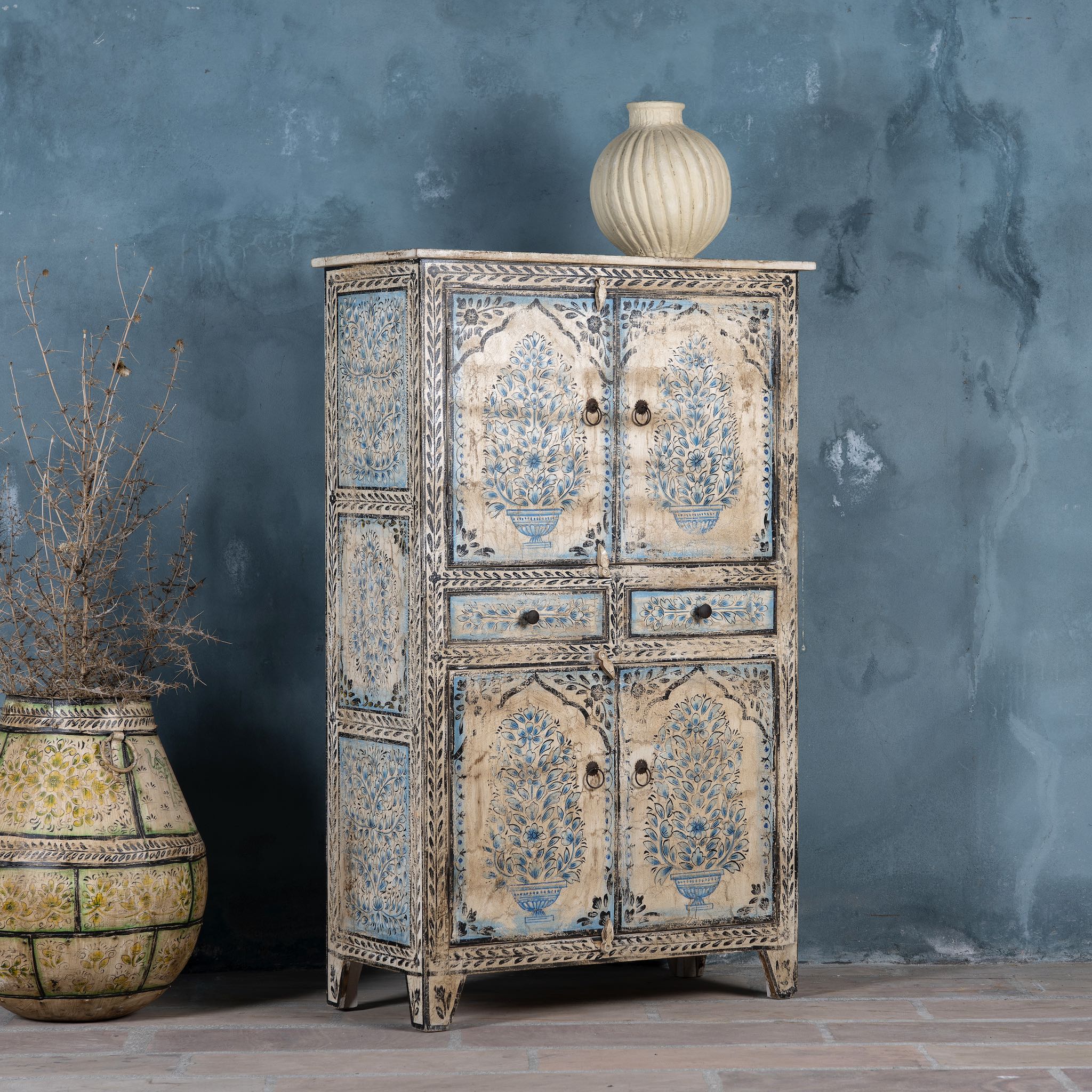 Side angle view of a vintage-style cabinet made from reclaimed wood, featuring intricate hand-painted floral vases in soft blue tones and distressed black detailing for an artisanal heritage look.
