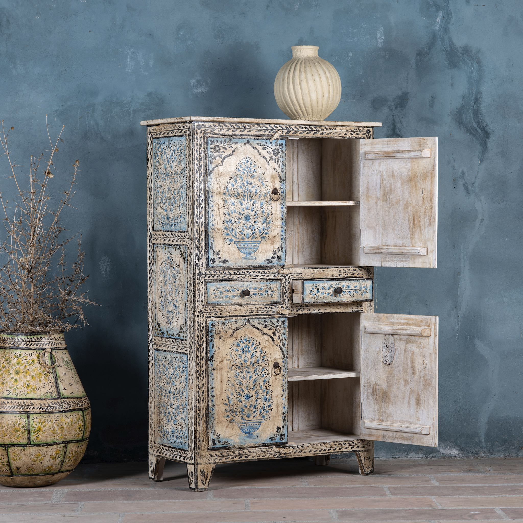 Open door picture of a vintage-style cabinet made from reclaimed wood, featuring intricate hand-painted floral vases in soft blue tones and distressed black detailing for an artisanal heritage look.