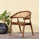 Side angle image of an acacia wood chair with curved frame and woven rattan backrest, elegant wooden armchair, 60 × 45 × 90 cm.