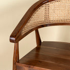 Close up image of an acacia wood chair with curved frame and woven rattan backrest, elegant wooden armchair, 60 × 45 × 90 cm.