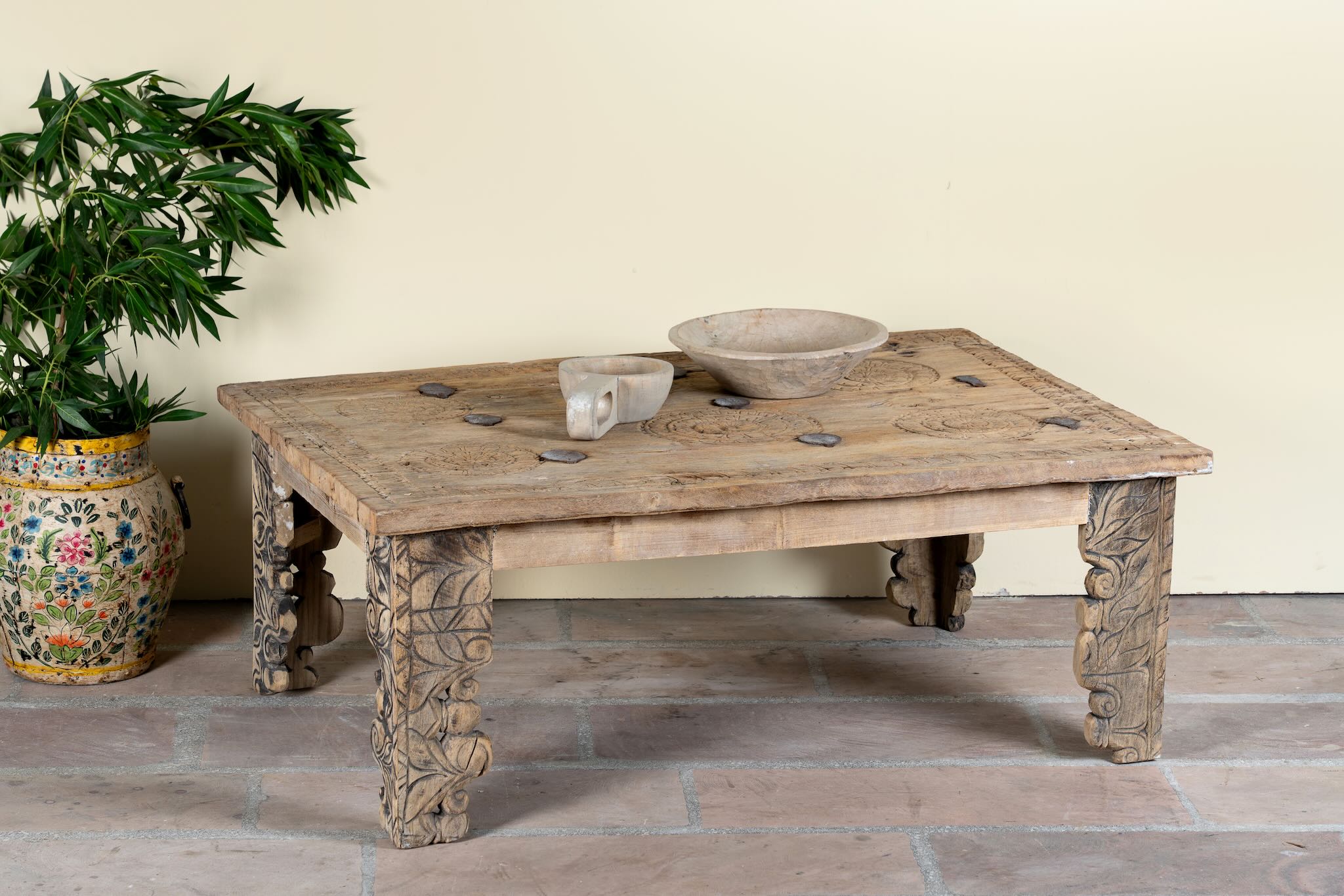 Side angle image of a sandblasted teak wood coffee table crafted from a hand-carved antique Indian door, featuring intricate traditional motifs and a rustic finish. A reclaimed wood furniture piece that blends cultural heritage with sustainable design.