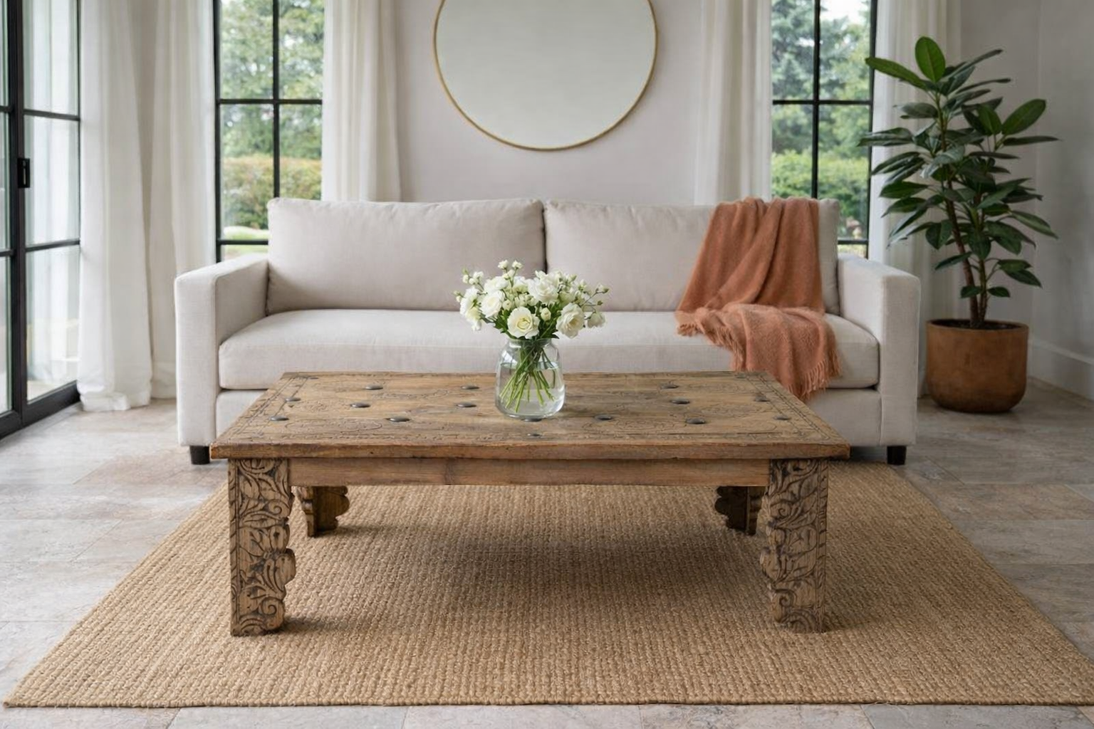 Lifestyle imagination of a of a sandblasted teak wood coffee table crafted from a hand-carved antique Indian door, featuring intricate traditional motifs and a rustic finish. A reclaimed wood furniture piece that blends cultural heritage with sustainable design.