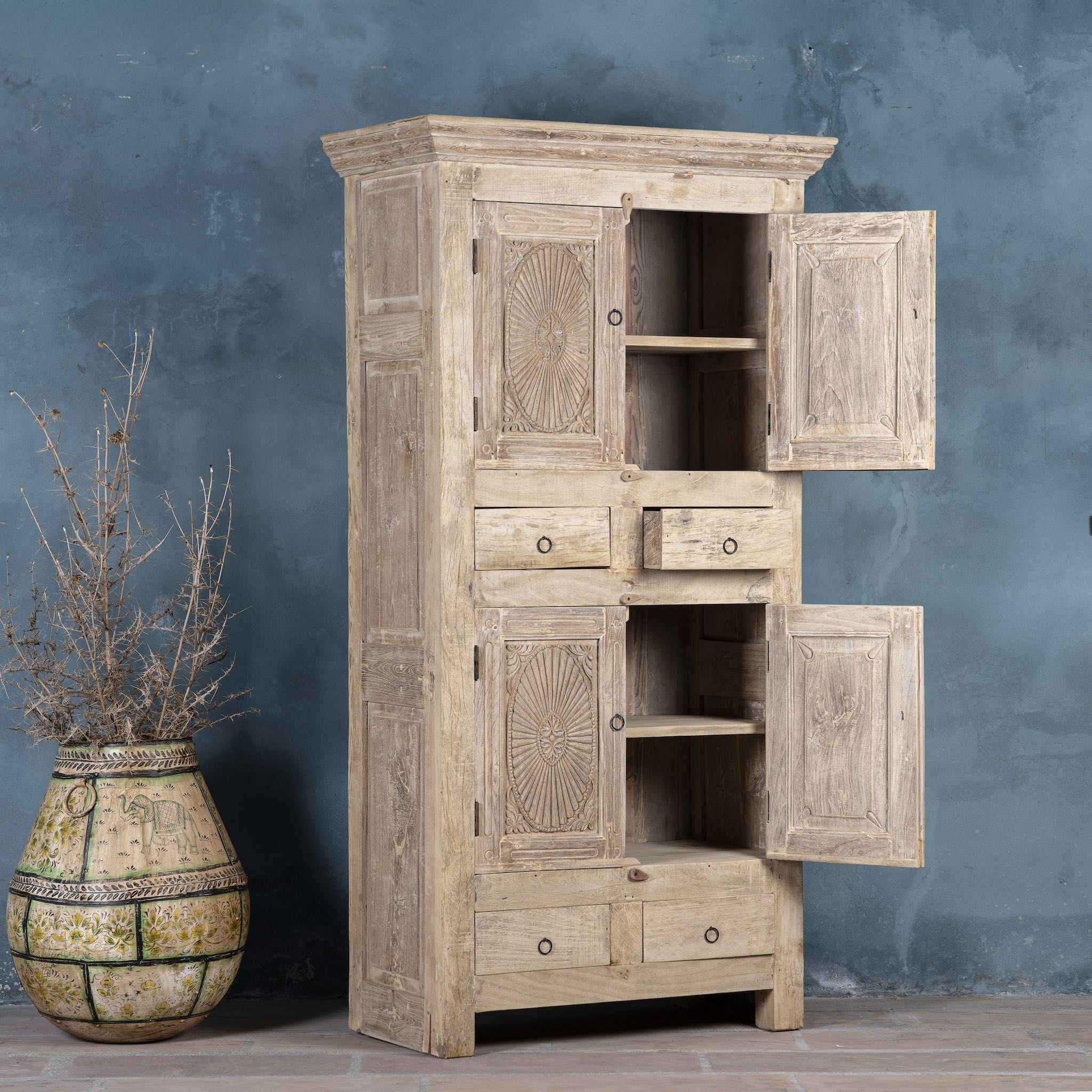 Open door picture of a wardrobe made from reclaimed wood with a sandblasted finish, featuring four carved doors, six drawers, and a light, rustic look in timeless Ibiza style.