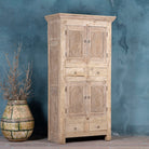 Side angle view of a wardrobe made from reclaimed wood with a sandblasted finish, featuring four carved doors, six drawers, and a light, rustic look in timeless Ibiza style.
