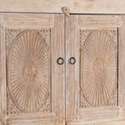 Close up picture of a wardrobe made from reclaimed wood with a sandblasted finish, featuring four carved doors, six drawers, and a light, rustic look in timeless Ibiza style.