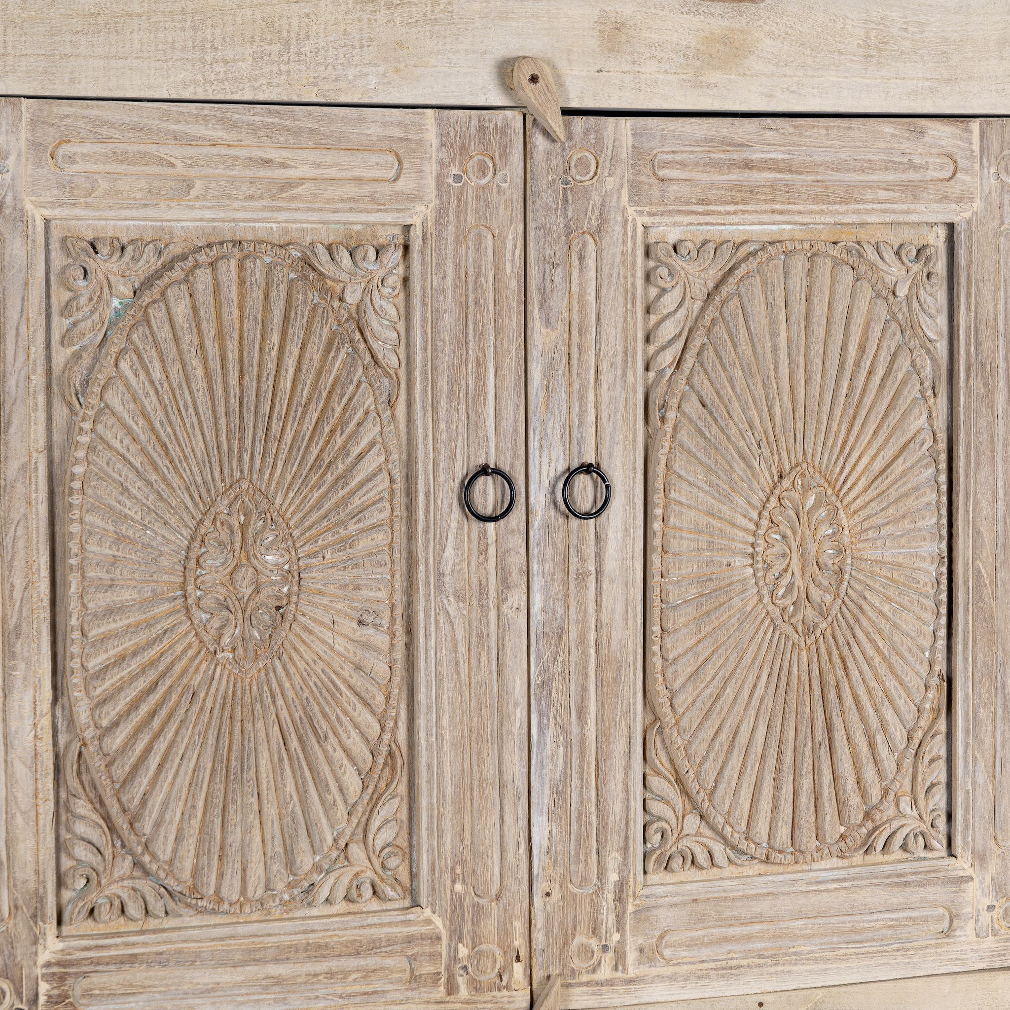 Close up picture of a wardrobe made from reclaimed wood with a sandblasted finish, featuring four carved doors, six drawers, and a light, rustic look in timeless Ibiza style.