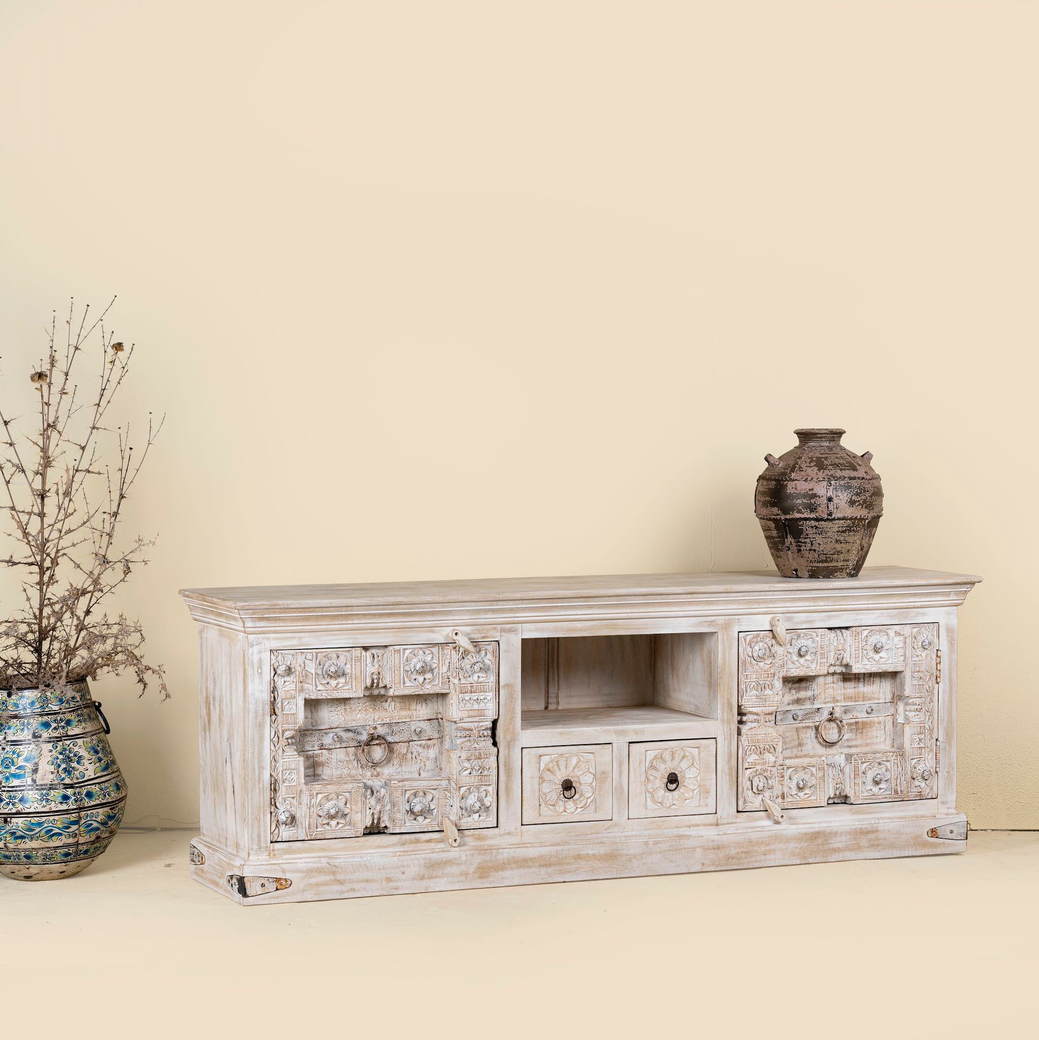 Side angle image of a wood carved sideboard made from antique teak and mango wood, whitewashed Indian furniture, Rewa design, 180 × 40 × 70 cm.