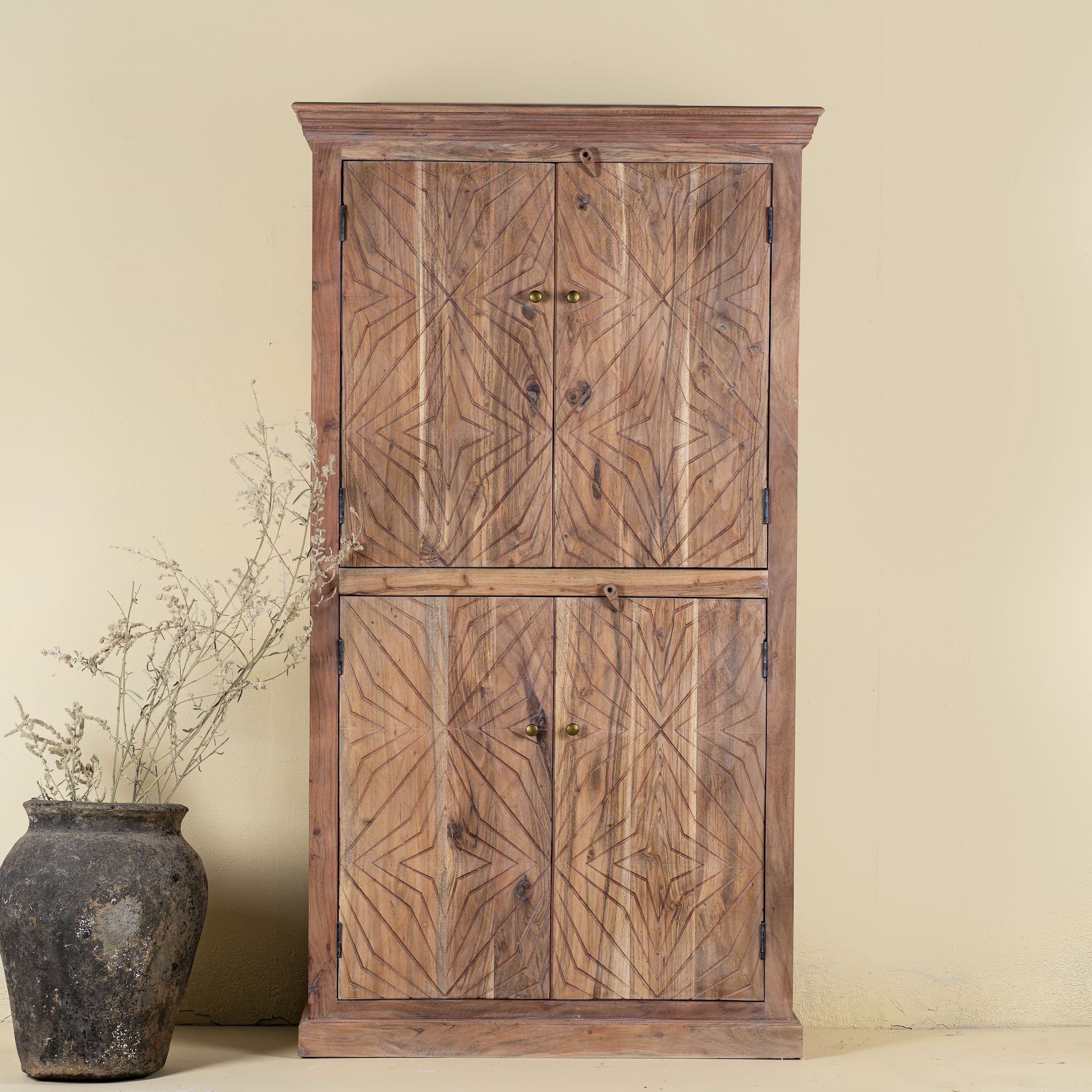 Front view of a hand crafted acacia wood cabinet with 4 doors, brass fitted door knobs and floral carvings.