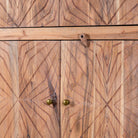 Close up view of a hand crafted acacia wood cabinet with 4 doors, brass fitted door knobs and floral carvings.