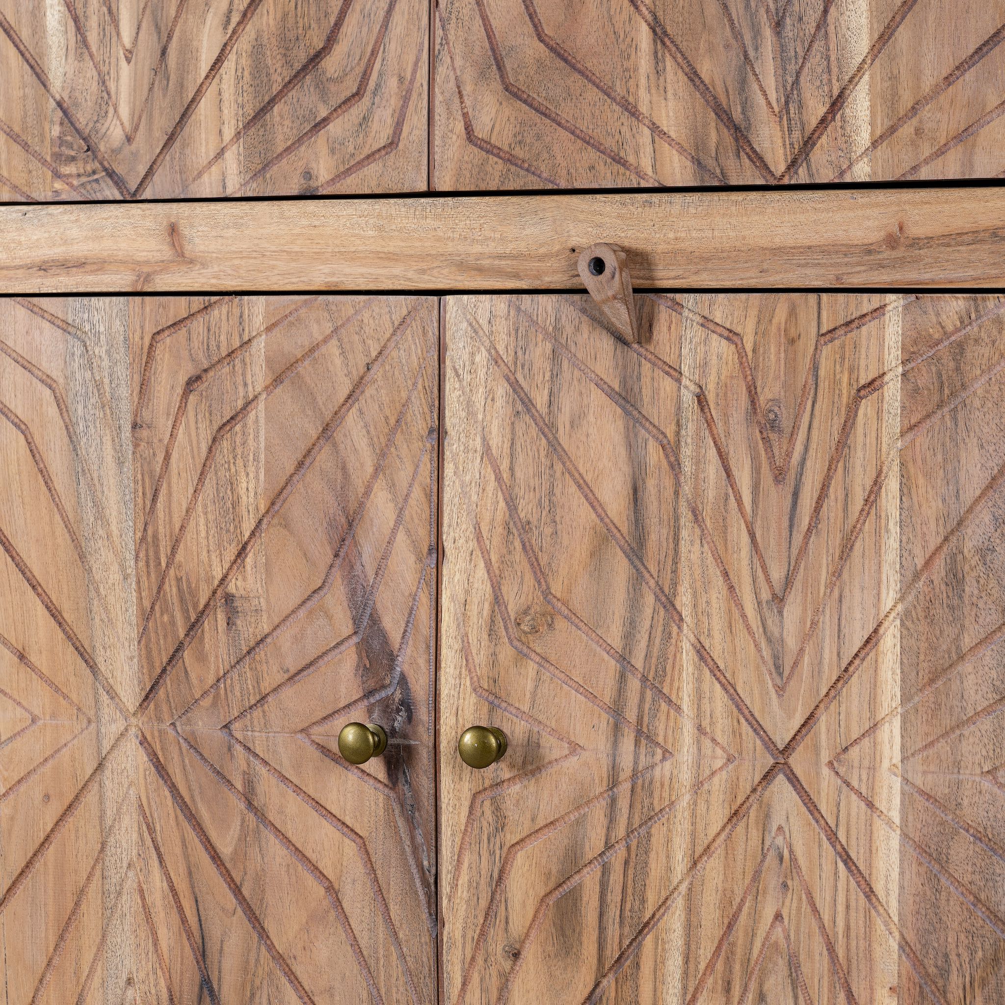 Close up view of a hand crafted acacia wood cabinet with 4 doors, brass fitted door knobs and floral carvings.