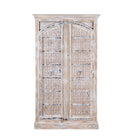 White background picture of a cabinet made from an old teak door, featuring intricate hand-carved floral panels and a whitewashed finish- a striking piece with vintage charm and Ibiza style elegance.

