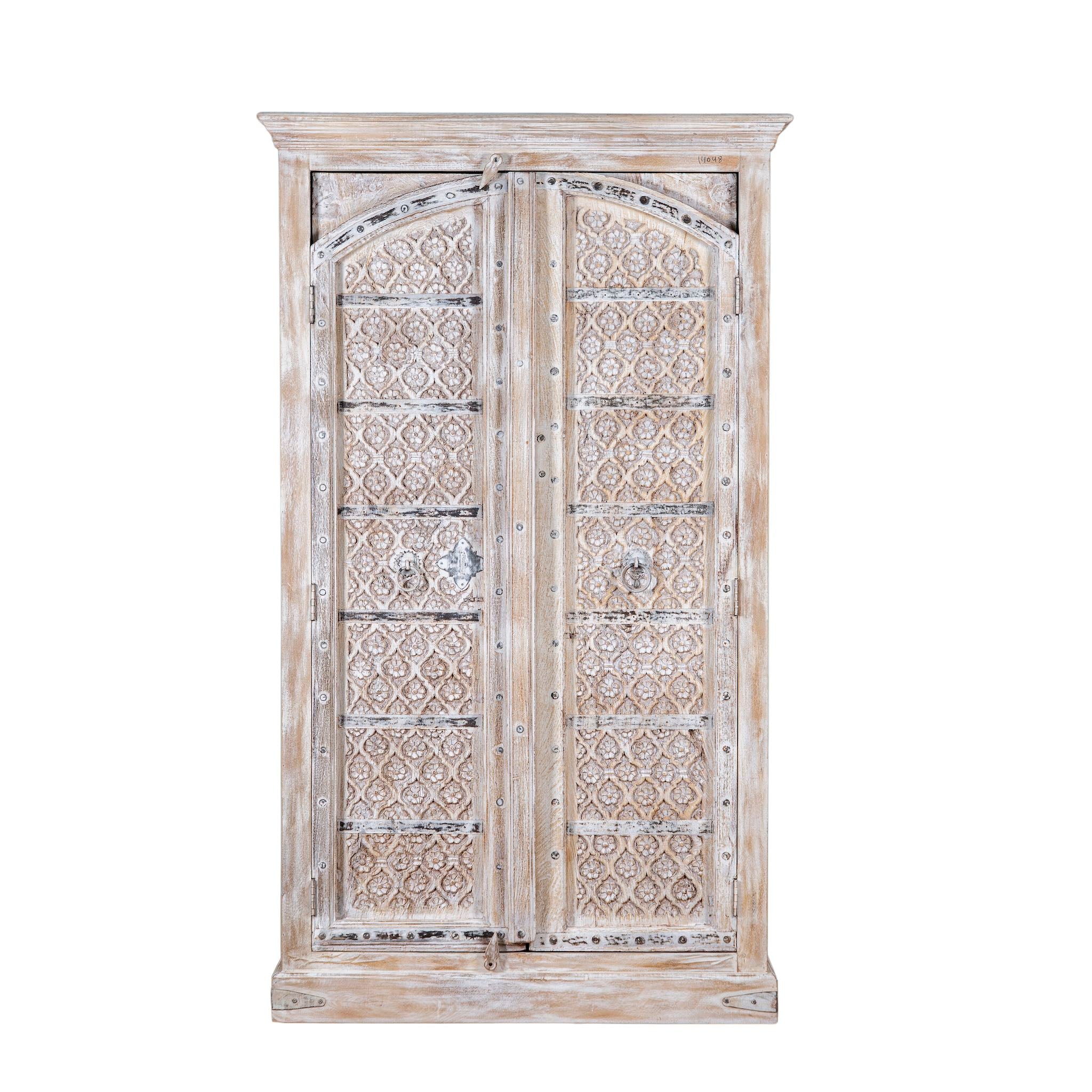 White background picture of a cabinet made from an old teak door, featuring intricate hand-carved floral panels and a whitewashed finish- a striking piece with vintage charm and Ibiza style elegance.

