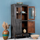 Side angle image with open doors of a shabby chic grey teak wood cabinet with glass doors and drawers – sustainable furniture for classic, rustic, or vintage interiors.