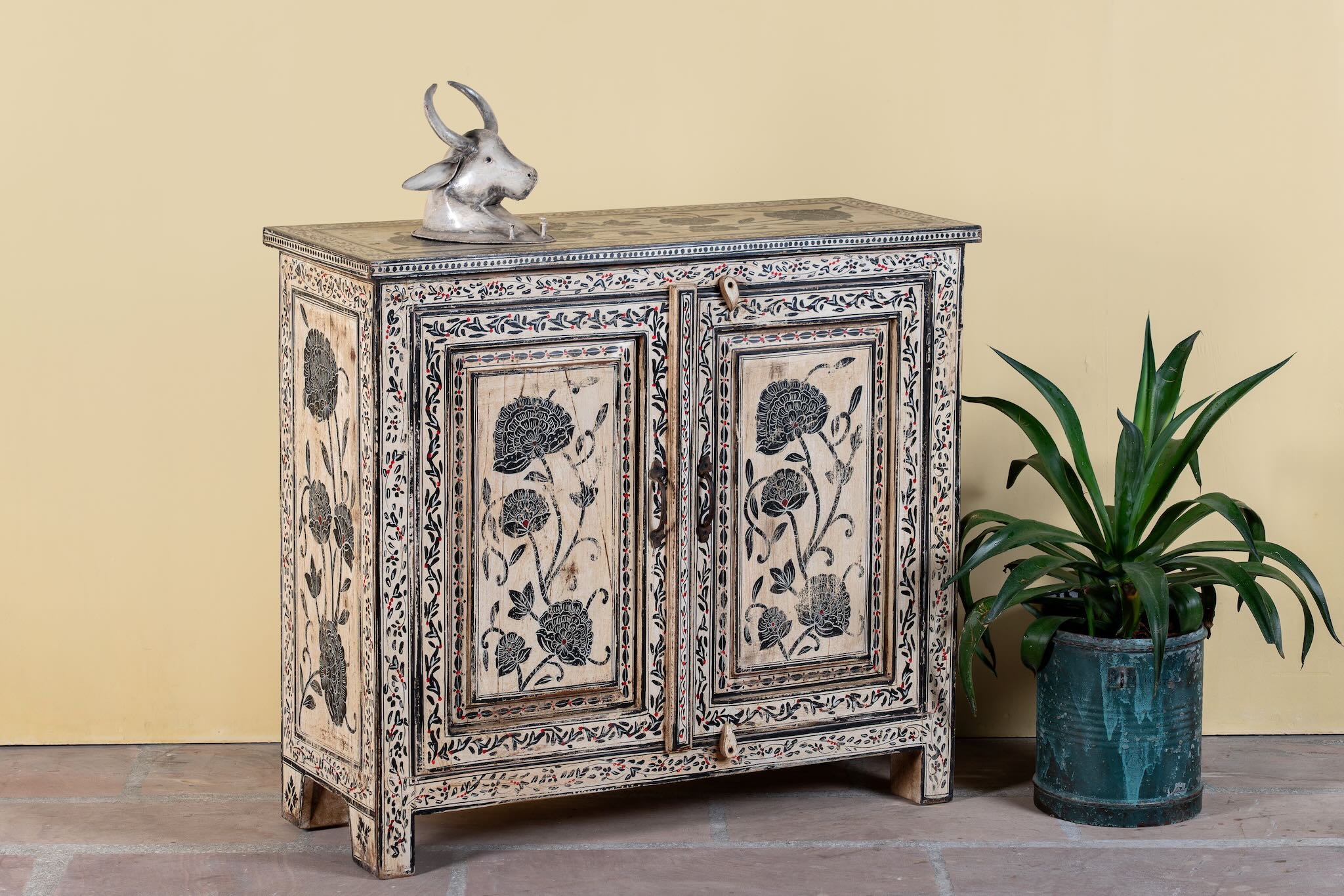 Side angle image of a hand-painted cupboard made from reclaimed wood with Indian floral motifs; ideal for boho chic living room or unique furniture decor, 100 × 92 × 36 cm.
