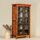 Side angle image of a hand-painted reclaimed wood showcase with floral motifs and glass doors – sustainable furniture combining vintage charm and traditional craftsmanship.