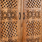 Close up image of a hand-carved mango wood wardrobe with floral and lattice motifs – a detailed piece of carved wood furniture ideal for natural mango wood interiors.