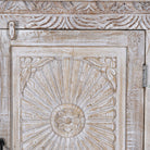 Close up image of a white washed wood cabinet with hand-carved floral design, Moroccan-style reclaimed wood furniture, 134 × 60 × 45 cm.