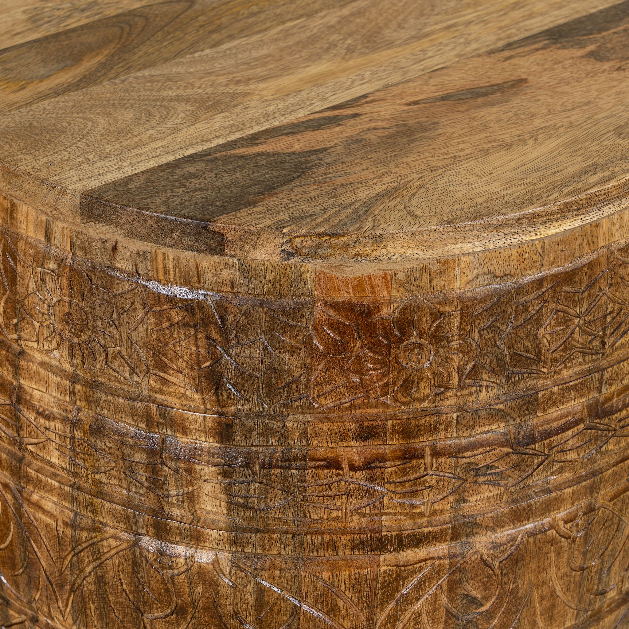 Close up picture of a elegant round hand carved coffee table made of sustainable Mango wood with floral design and black marble top.