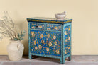 Side anle image of a hand-painted cupboard made of reclaimed wood with vibrant floral design – Tvesa model by Om Home & Garden