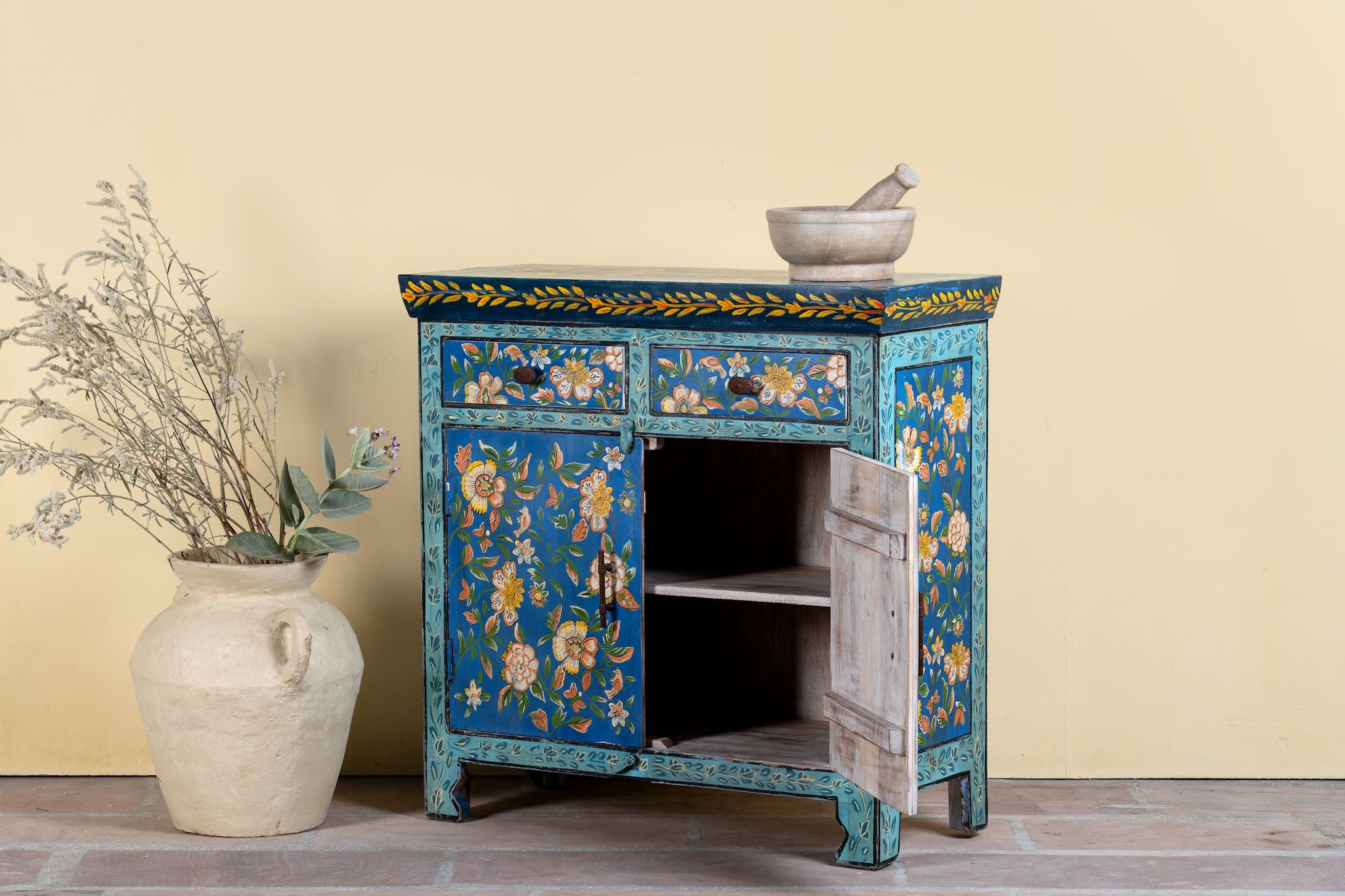 Side angle image with open door of a hand-painted cupboard made of reclaimed wood with vibrant floral design – Tvesa model by Om Home & Garden
