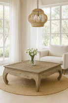 Lifestyle imagination of a square hand carved mango wood coffee table with floral top and vintage multi-layer finish; 120 × 120 × 45 cm.