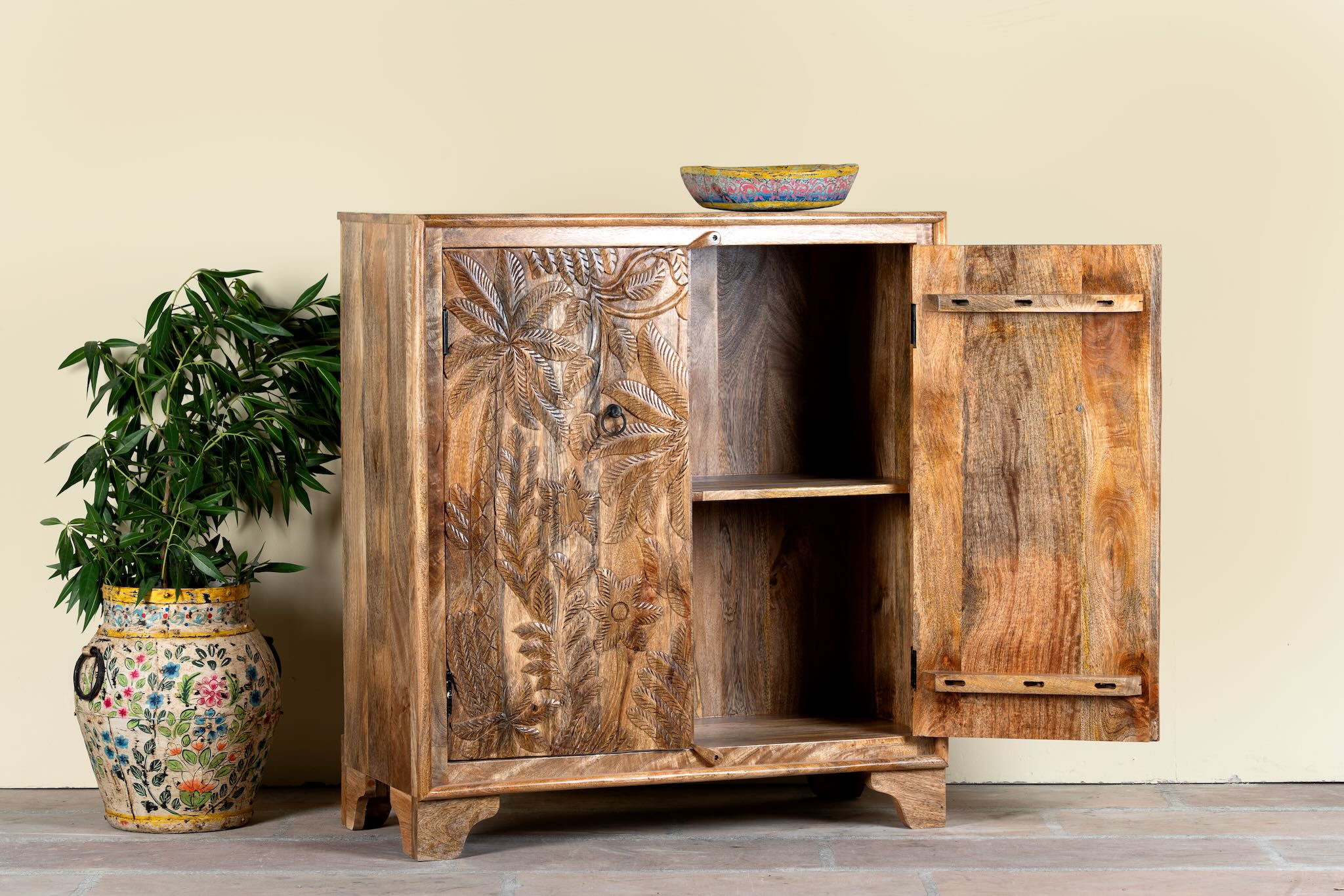Side angle image with open door of a Hand-carved mango wood cupboard Vansh with double doors featuring intricate floral and botanical motifs. A Mediterranean-inspired piece of Indian furniture offering functional storage and timeless artisan detail.