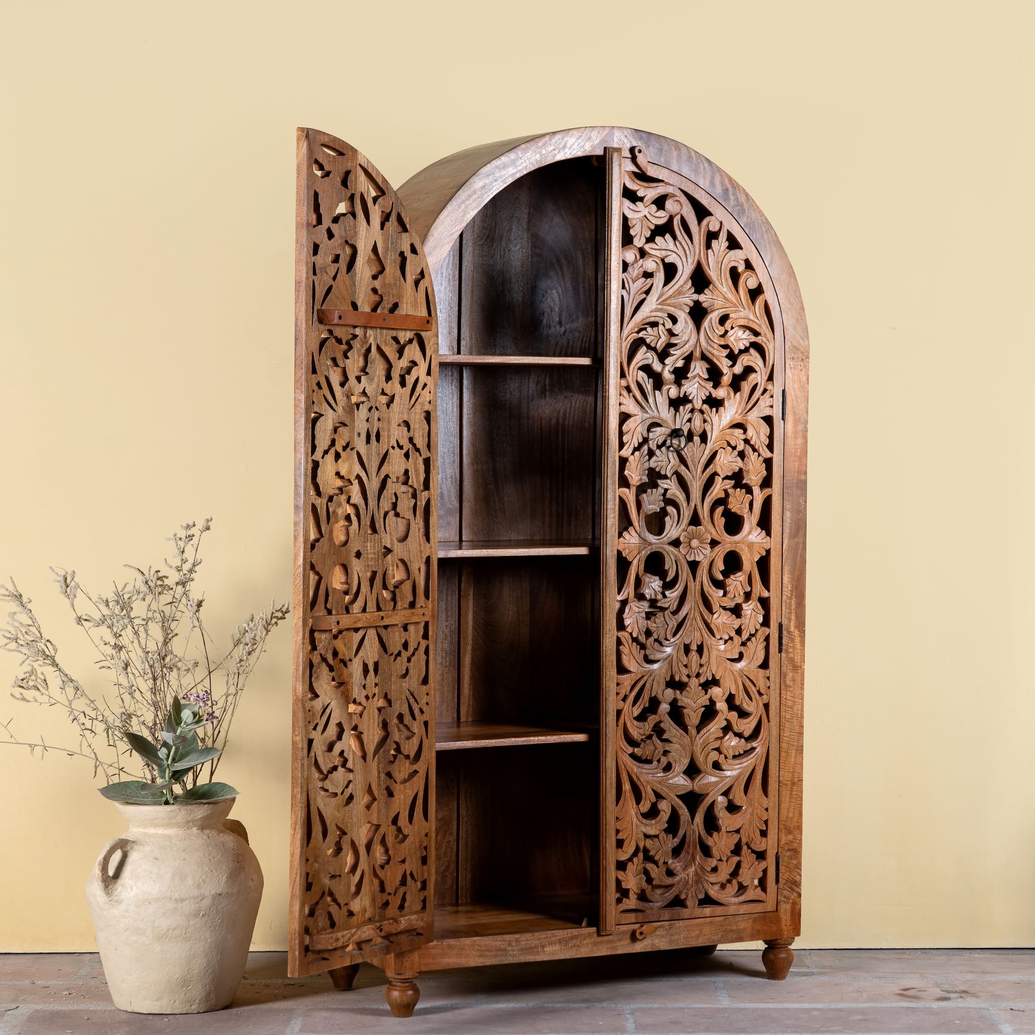 Side angle image with open door of a hand carved wooden wardrobe with arc-shaped cabinet design in solid mango wood – Aranya model by Om Home & Garden