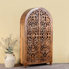 Side angle image of a hand carved wooden wardrobe with arc-shaped cabinet design in solid mango wood – Aranya model by Om Home & Garden