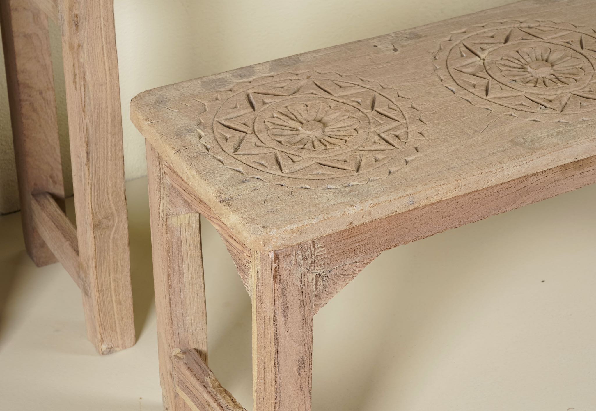 Close up image of a vintage school bench set from India, crafted from old teak wood, featuring a simple, sturdy design with a long bench and matching table in a natural, weathered finish, styled in a neutral-toned interior with rustic decor accents.
