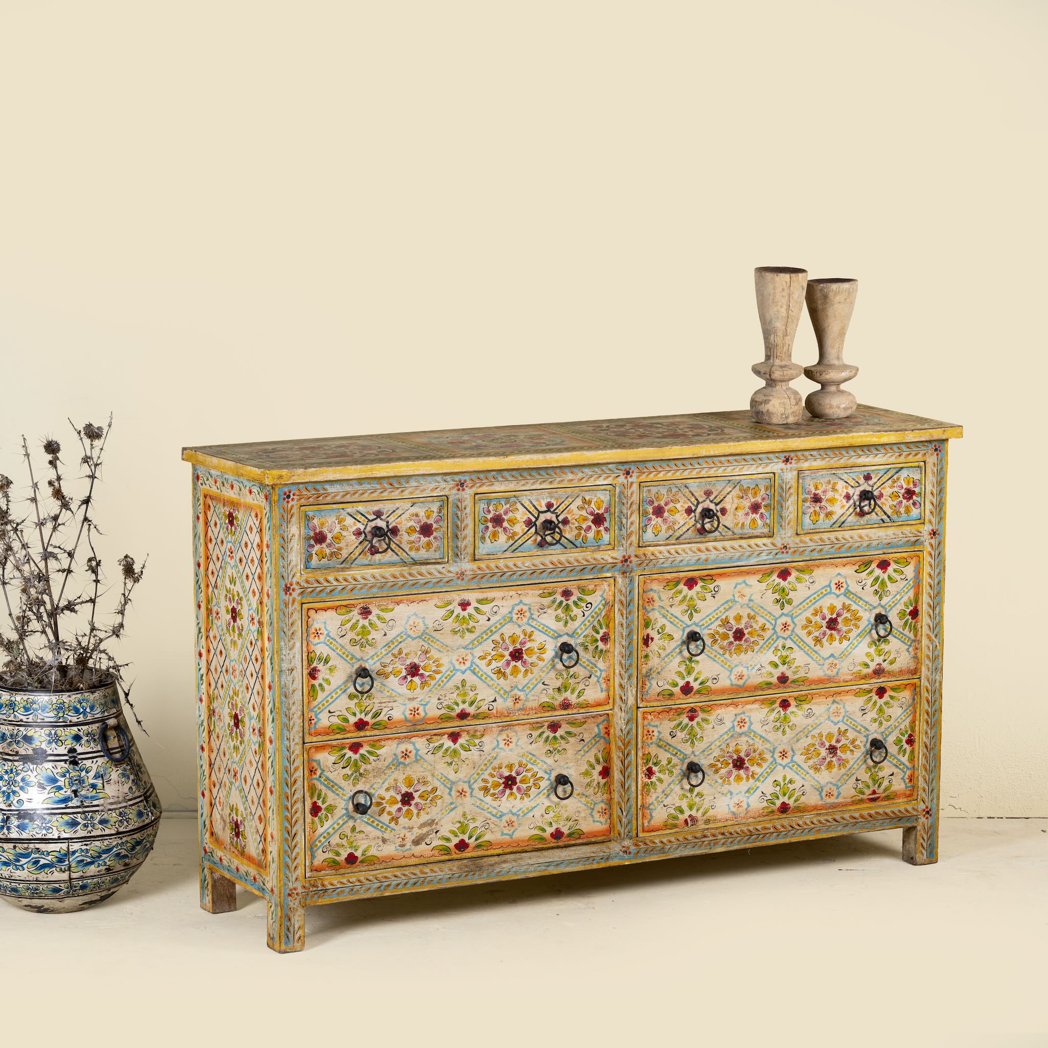 Side angle image of a Ziya hand‑painted chest of 8 drawers made from reclaimed wood with floral motifs and iron handles—an artisan piece of painted wooden furniture.