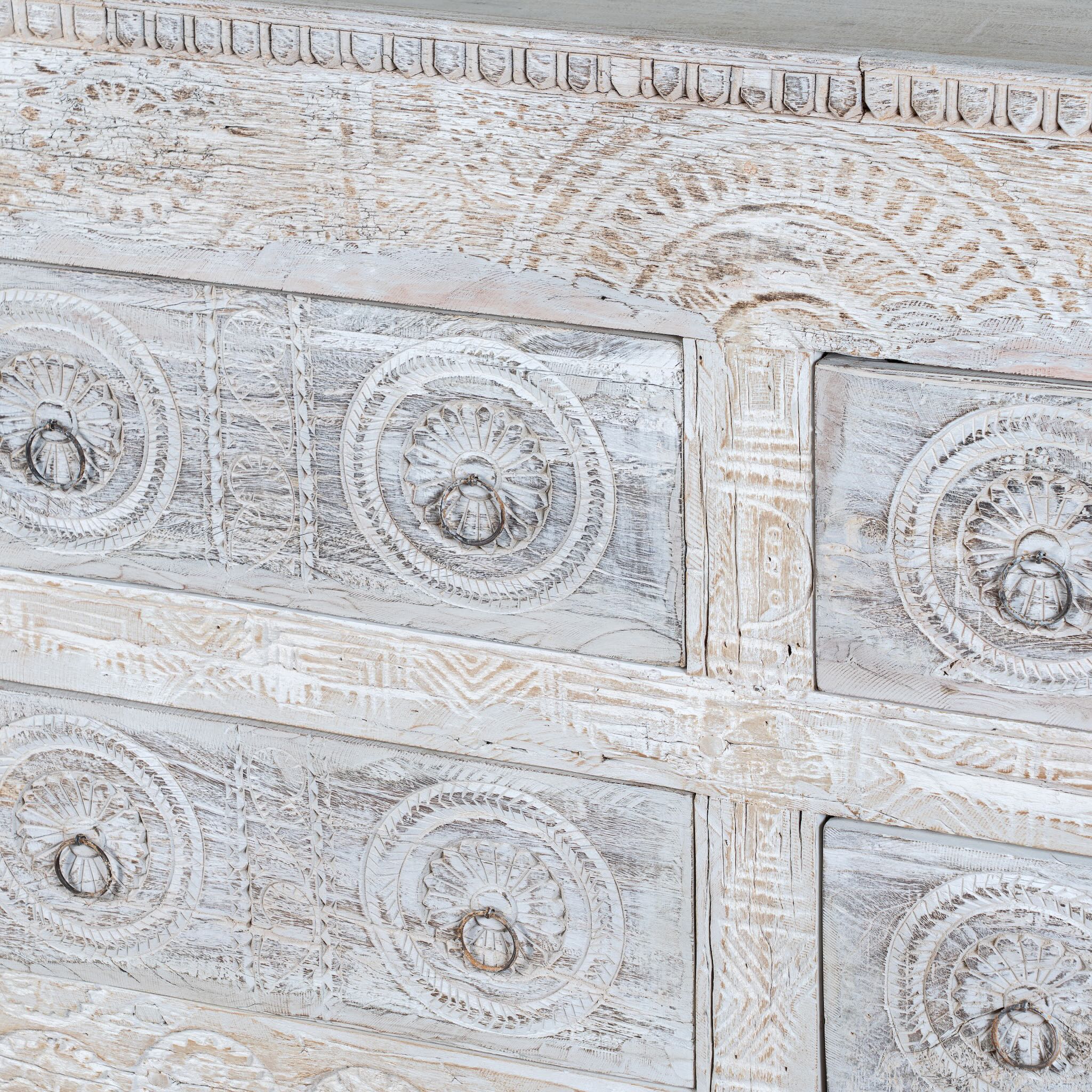 Close up image of a handcrafted chest of drawers Zuber made from reclaimed wood, featuring six carved drawers with circular motifs and a whitewashed finish. A rustic, sustainable furniture piece with soft texture and elegant detailing.