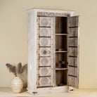 Open door view of a old teak door wardrobe with floral carvings and original iron fittings.